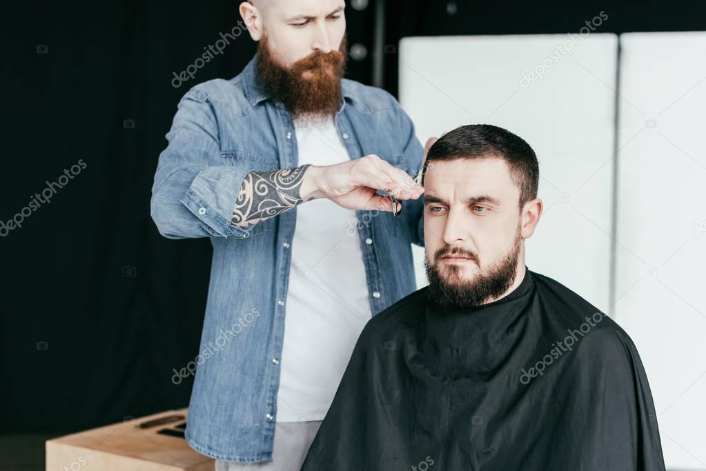 barber cutting serious customer hair at barbershop