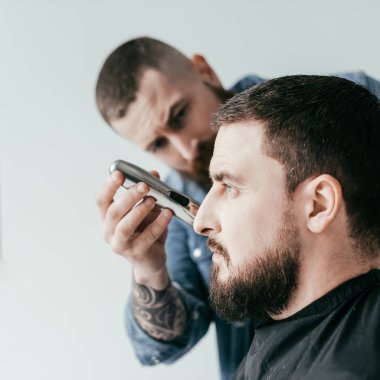 Kuaför düzeltme müşteri sakal üzerine beyaz izole berber, yan görünüm