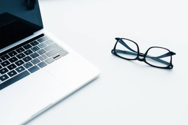 Laptop with blank screen and eyeglasses beside, minimalistic conception clipart