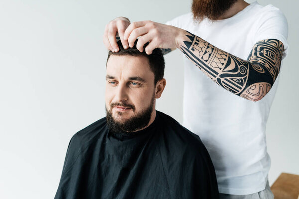 cropped image of barber styling customer hair at barbershop isolated on white