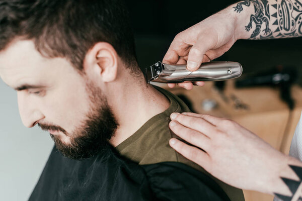 cropped image of barber shaving customer hair at barbershop
