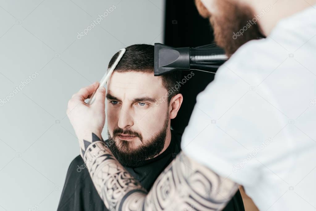 cropped image of barber drying customer hair at barbershop