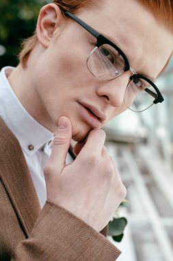 Kameraya bakarak gözlük Kızıl saçlı düşünceli genç adam portresi