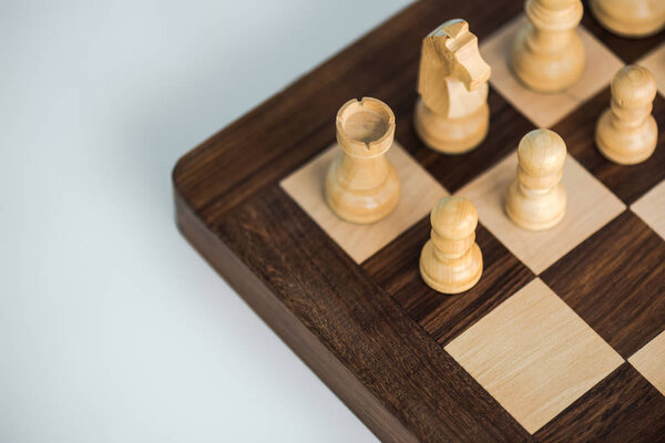 Cropped image of chess board with white chees pieces on white surface