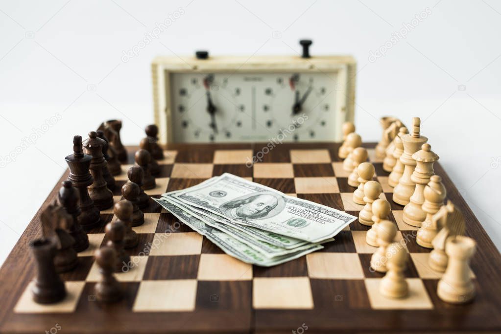 Chess board with cash and figures near chess clock isolated on white