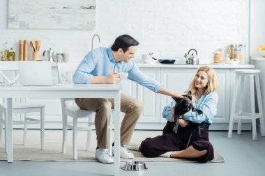 Eller laptop ve okşayarak Fransız köpek ile tabloya göre otururken kahve içme adam