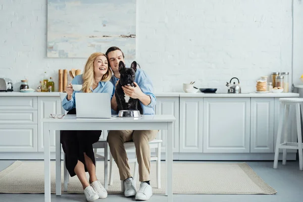 Casal Sorridente Com Café Sentado Mesa Com Laptop Cozinha Acariciando — Fotografia de Stock