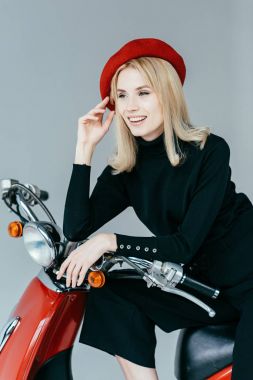 Gri yalıtılmış bağbozumu scooter üzerinde eğilerek şık güzel kadın
