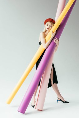 Elegant blonde girl holding colorful paper rolls clipart