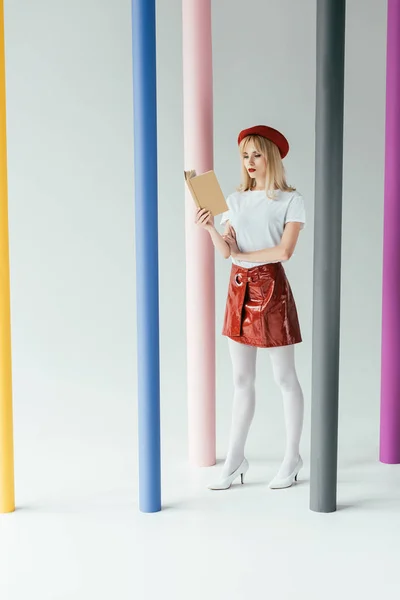 Atractiva Joven Leyendo Libro Posando Por Coloridos Pilares — Foto de Stock