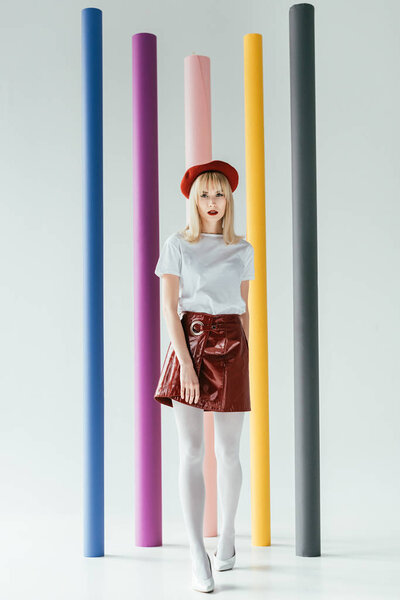 Stylish pretty woman in vintage style clothes in front of colorful columns