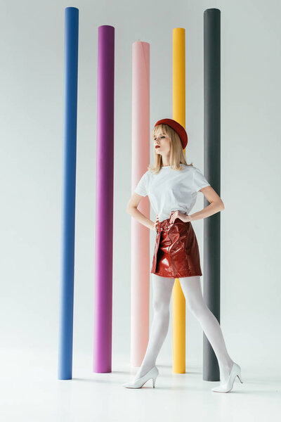 Elegant blonde girl in vintage style clothes in front of colorful columns
