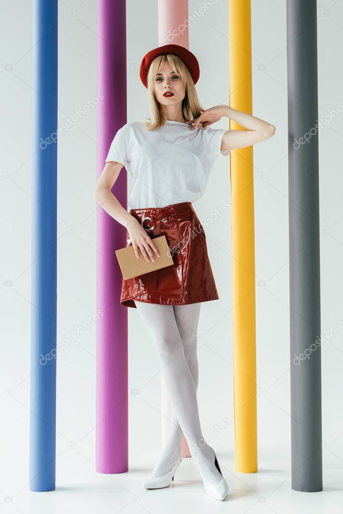 Stylish pretty woman posing by colorful pillars