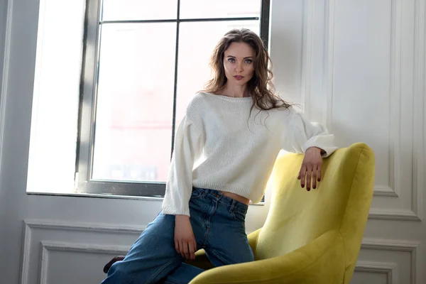 Beautiful Brunette Girl Denim Pants Leaning Yellow Armchair Looking Camera — Stock Photo, Image