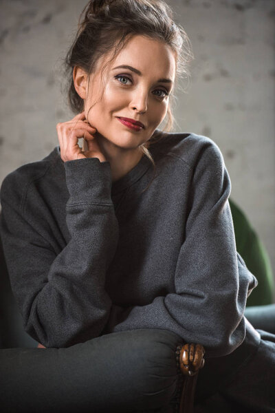 portrait of beautiful brunette woman in grey sweater smiling at camera 