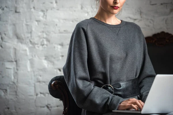 屋内でラップトップを使用してスタイリッシュなセーターの女性のクロップ撮影  — 無料ストックフォト