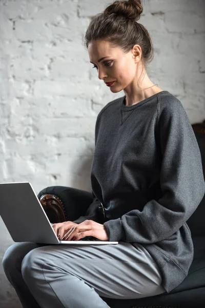 使用笔记本电脑的灰色衣服美丽的浓缩妇女 — 图库照片