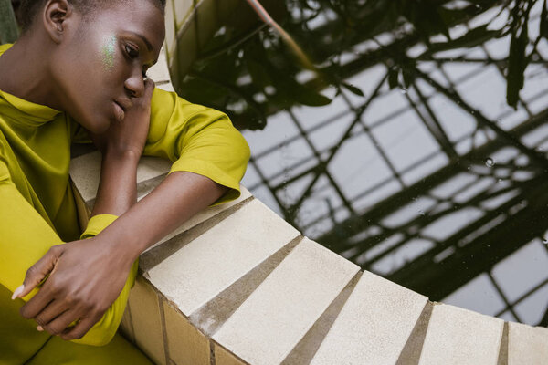 Beautiful style african american model with glitter makeup posing near pool