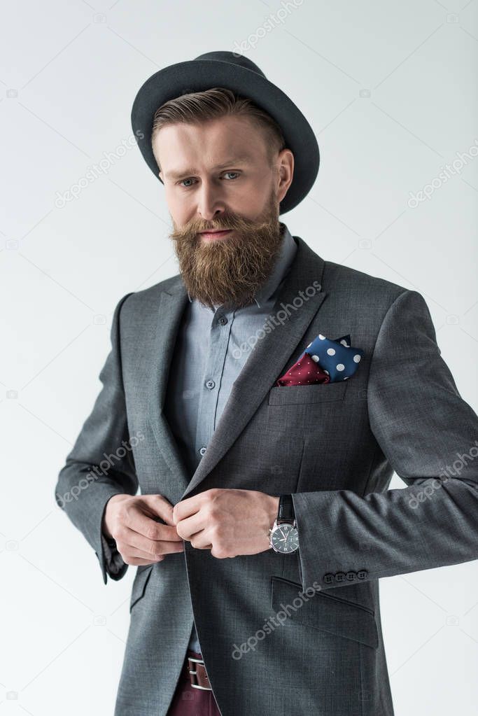 Man with vintage mustache and beard buttoning his jacket isolated on light background