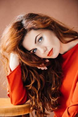 Dışkı izole kahverengi zemin üzerine yaslanmış çekici Kızıl saçlı kadın