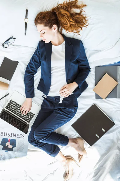 Ovanifrån Affärskvinna Kostym Att Skriva Laptop Liggandes Sängen Bland Mappar — Stockfoto