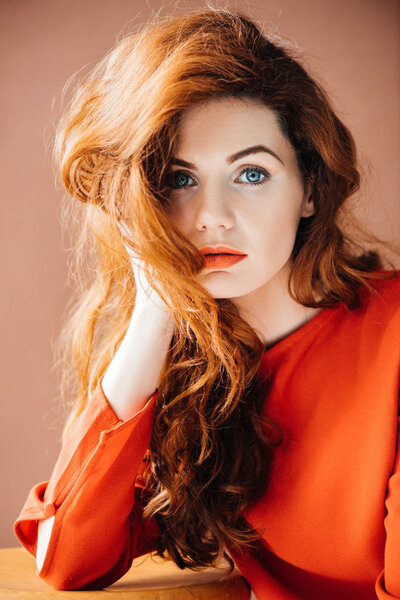 Красивая молодая девушка опираясь на руку изолированы на коричневом фоне
