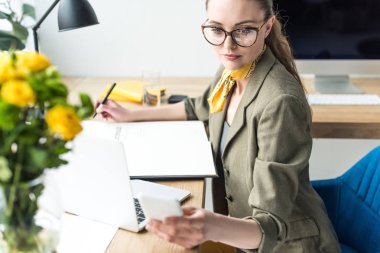 dizüstü bilgisayar ve akıllı telefon kullanma office gözlük güzel işkadını yüksek açılı görünüş