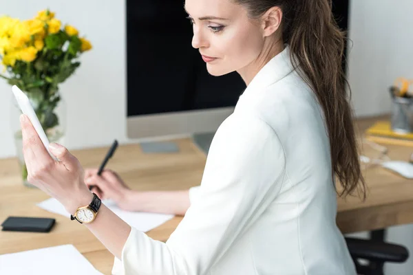 Vista Lateral Mujer Negocios Utilizando Teléfono Inteligente Mientras Hace Papeleo —  Fotos de Stock