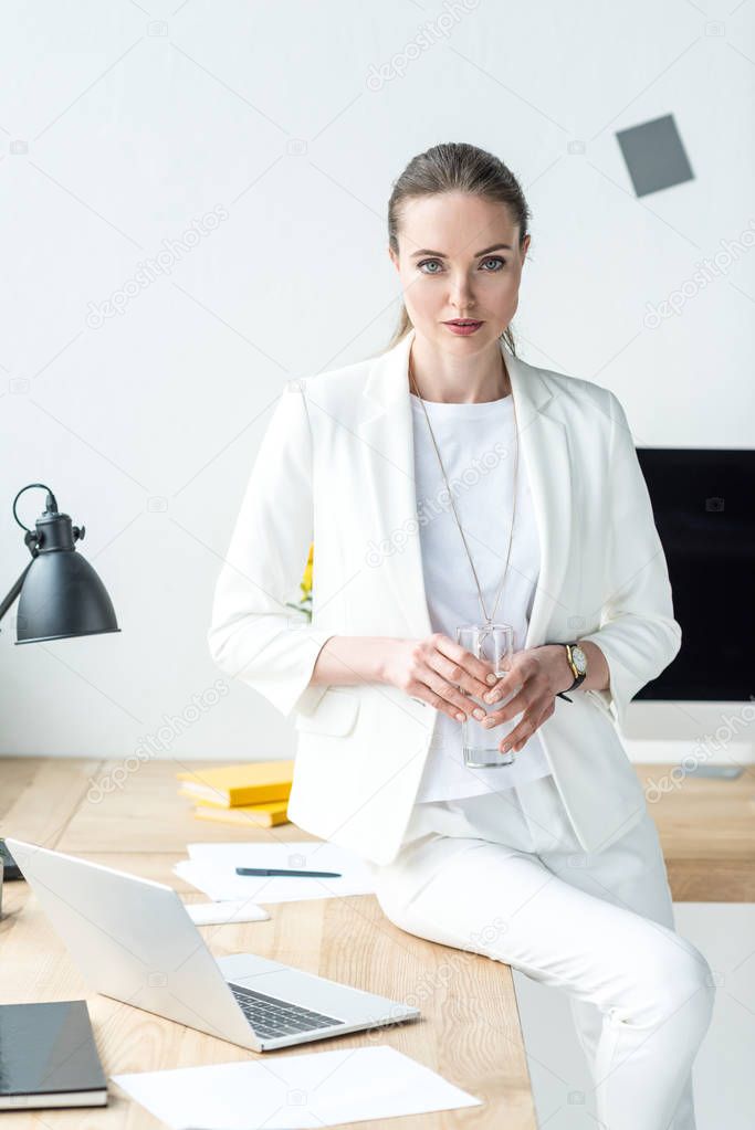 portrait of businesswoman with glass of water at workplace with laptop in office