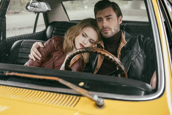 古臭い車に一緒に座っているジャケットをレザーでスタイリッシュな思いやりのある若いカップル — ストック写真