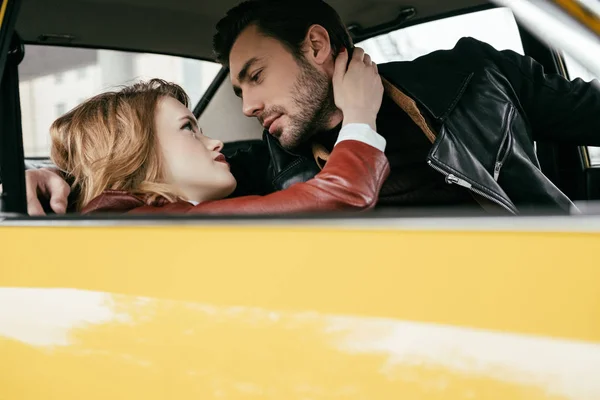 美丽的时尚年轻夫妇拥抱和看对方在车上 — 图库照片