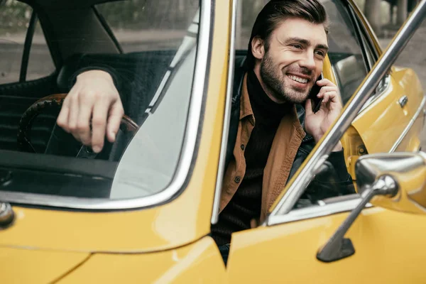 Krásný Usměvavý Mladý Muž Mluví Smartphone Zatímco Sedí Žluté Veteránem — Stock fotografie