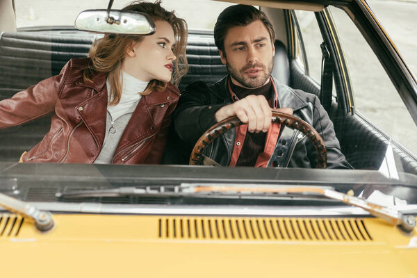 привлекательная девушка смотрит на стильный парень за рулем винтажного автомобиля
 