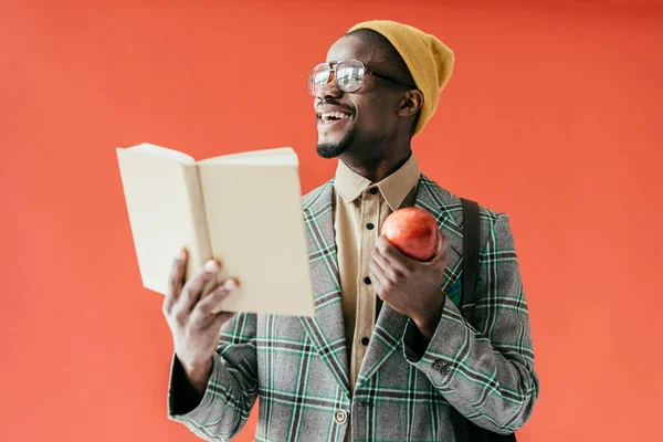 Eleganta Skrattande Afroamerikanska Mannen Med Boken Och Äpple Isolerad Röd — Stockfoto