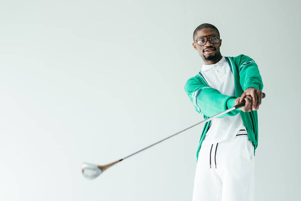 stylish african american man in retro sportswear playing golf, isolated on white