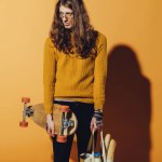 Beau patineur tenant longboard et sac avec nourriture, sur jaune