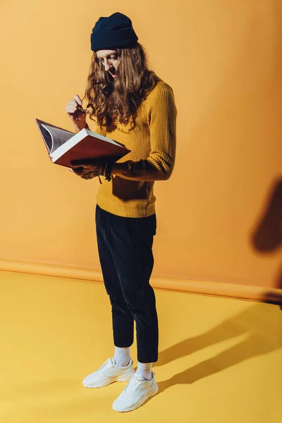 Elegante Man Met Lange Haren Lezen Boek Geel — Gratis stockfoto