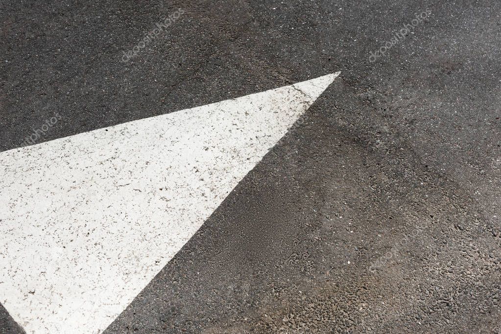 White painted arrow on asphalt road