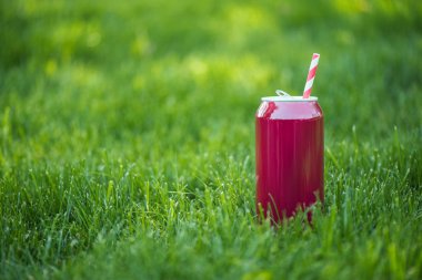 close up view of drink in pink can with straw on green lawn clipart