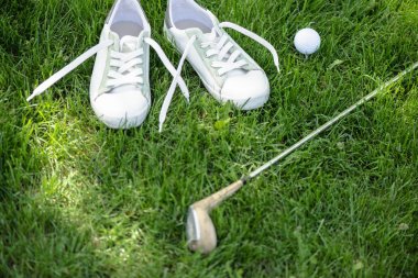 Yeşil sahada golf ekipmanları ve beyaz ayakkabı görünümü kadar kapatın