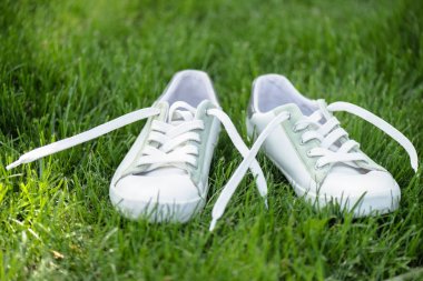 close up view of white stylish  shoes on green grass clipart