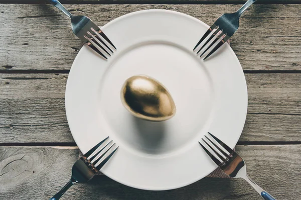 Œuf de Pâques doré sur assiette — Photo de stock