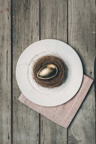 Œuf de Pâques doré sur assiette — Photo de stock