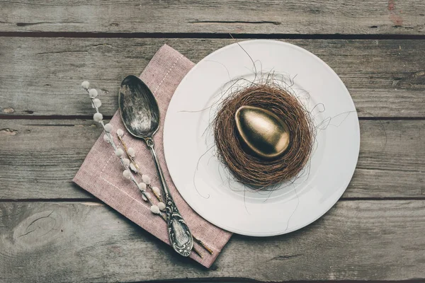 Œuf de Pâques doré sur assiette — Photo de stock