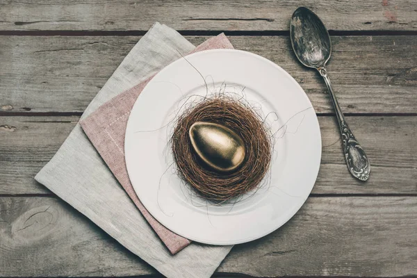 Œuf de Pâques doré sur assiette — Photo de stock