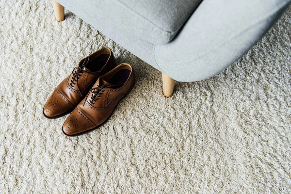Chaussures oxford sur tapis près du fauteuil — Photo de stock
