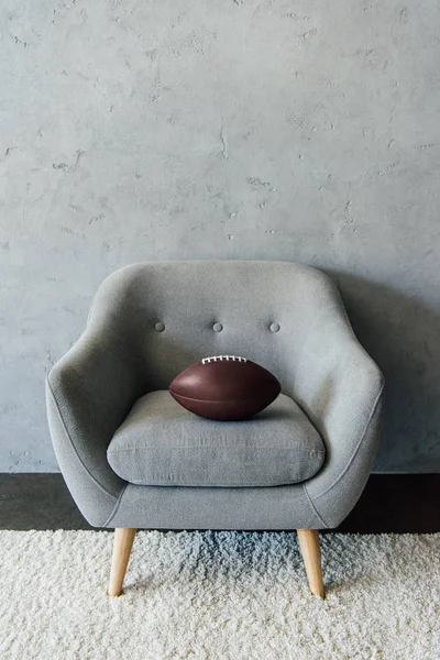 Pelota de fútbol americano en sillón gris - foto de stock