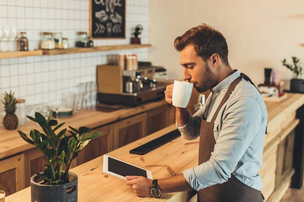 Barista com xícara de café usando tablet — Fotografia de Stock