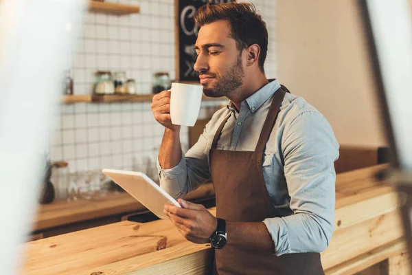 Barista with cup of coffee using tablet — Stock Photo
