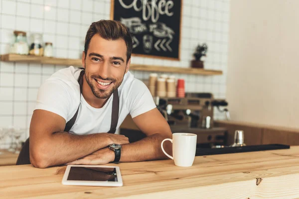 Barista sorridente al bancone con tablet — Foto stock